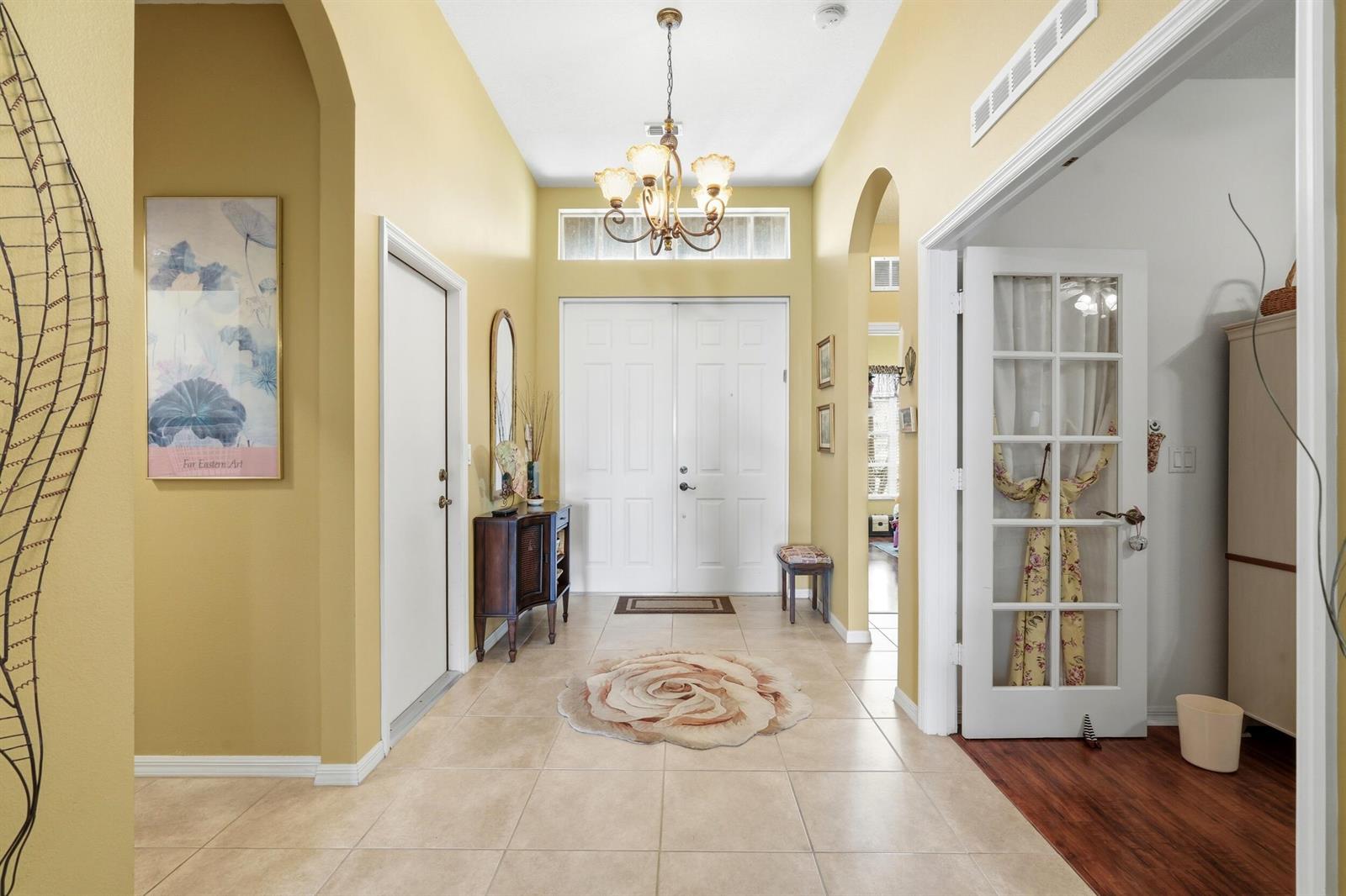 A bright entryway features tile flooring, a chandelier, double front doors, and yellow walls — 11031 SW Dunhill Court, FL 34987, FL