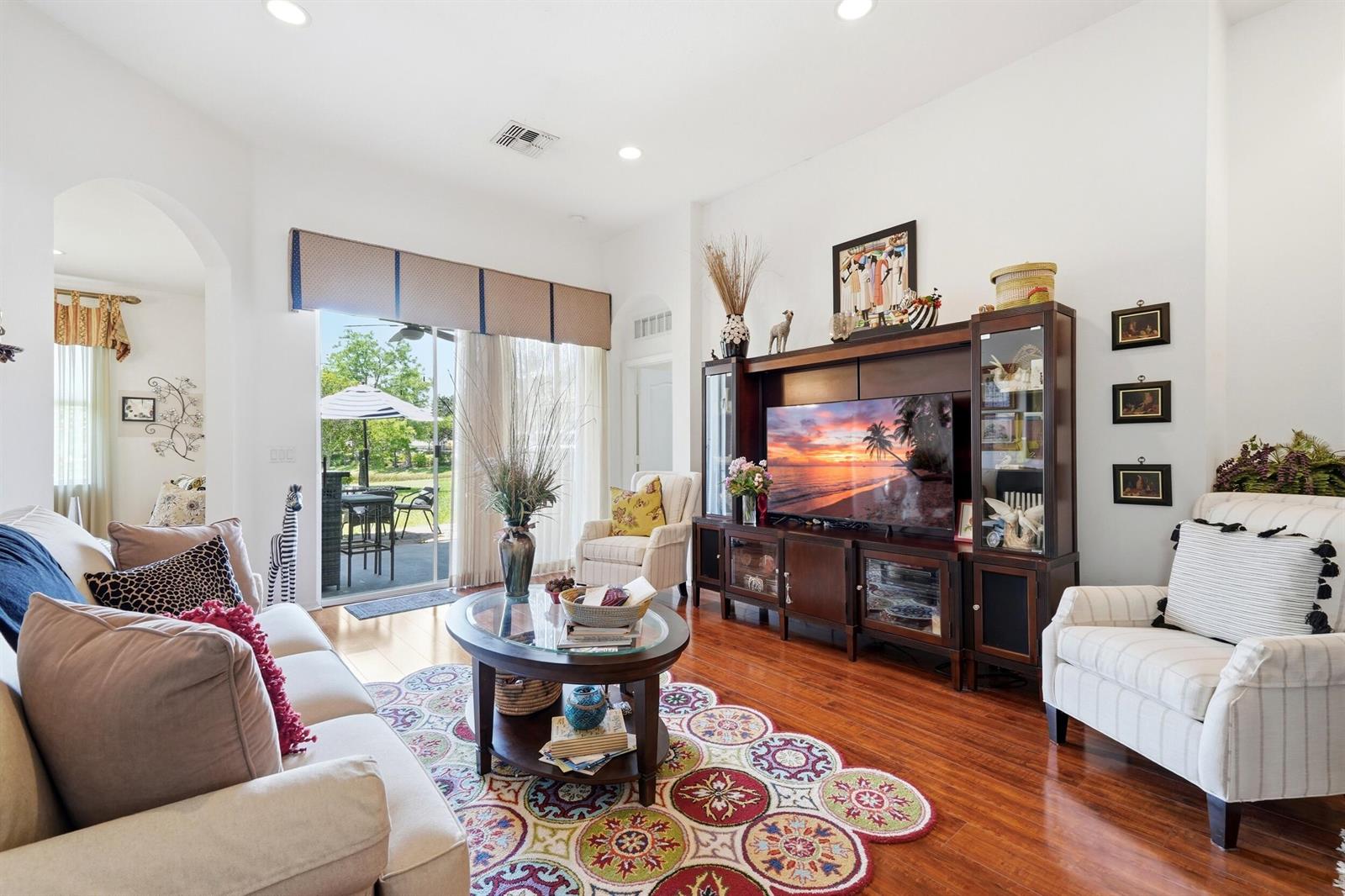 A living room features hardwood floors, a large entertainment center, and a sliding glass door — 11031 SW Dunhill Court, FL 34987, FL