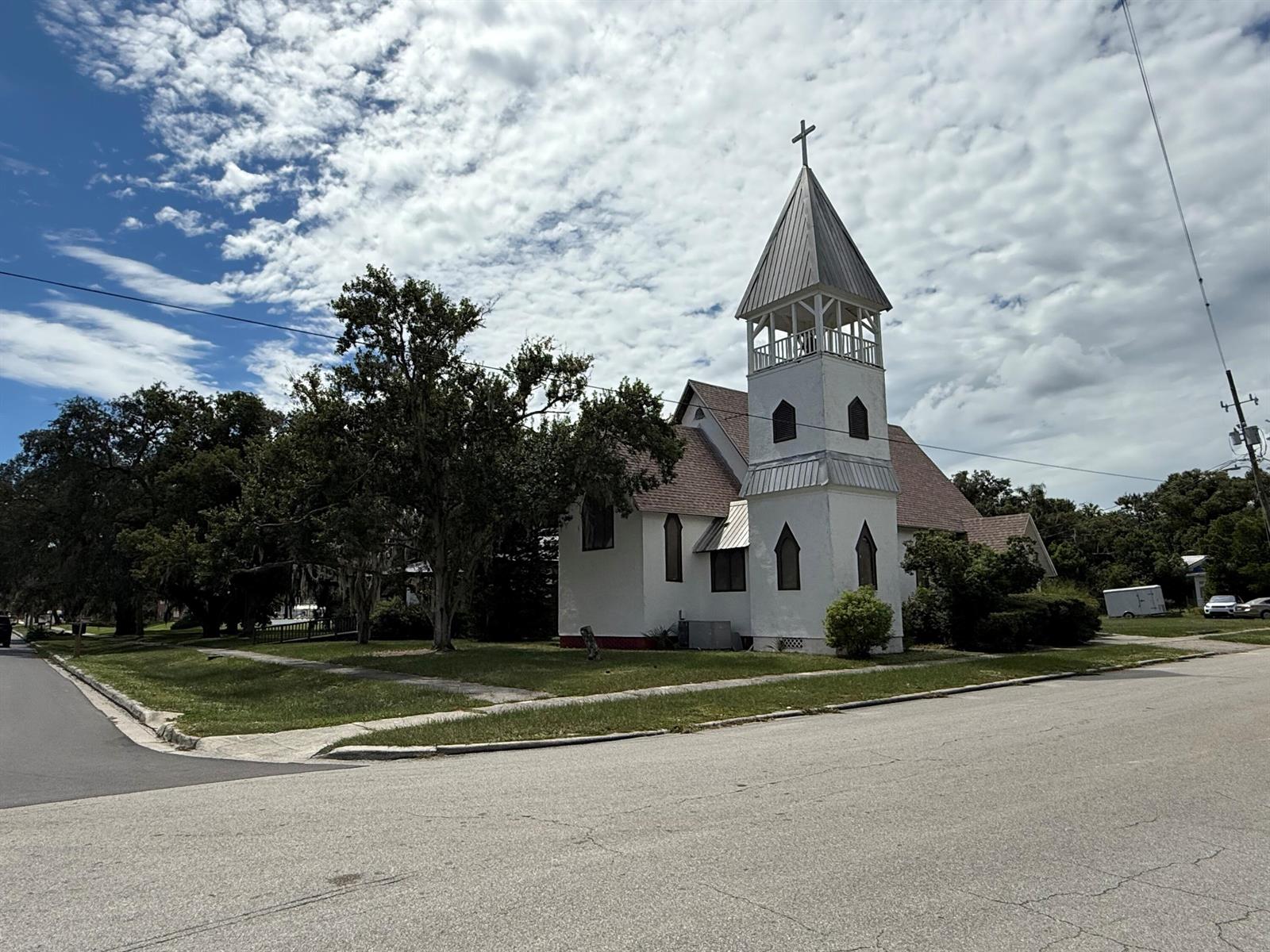 A white church with a steeple and cross stands on a grassy corner lot — 18 E Pleasant Street, FL 33825, FL