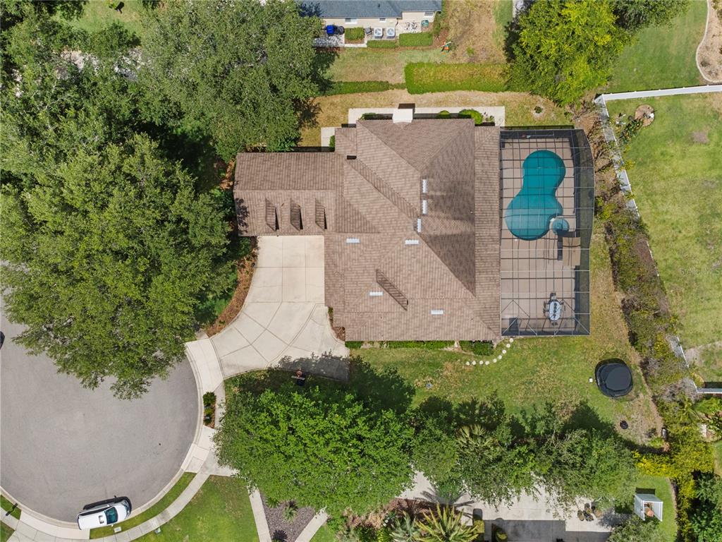 An aerial view shows a house with a shingled roof, driveway, and screened-in pool — 9527 QUEENSBURY COURT, WINDERMERE, FL