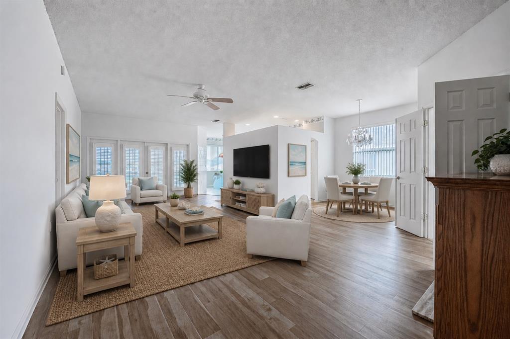 A bright living and dining area with white walls, light wood flooring, and neutral furniture — 6206 RES CIRCLE, LAKELAND, FL