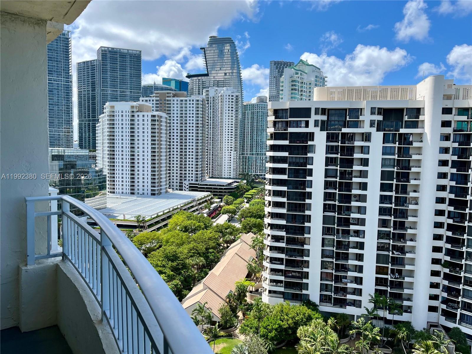 A balcony overlooks a dense urban landscape of high-rise apartment buildings and green trees — 770 Claughton Island Dr # 2009, Miami FL 33131, MIAMI, FL