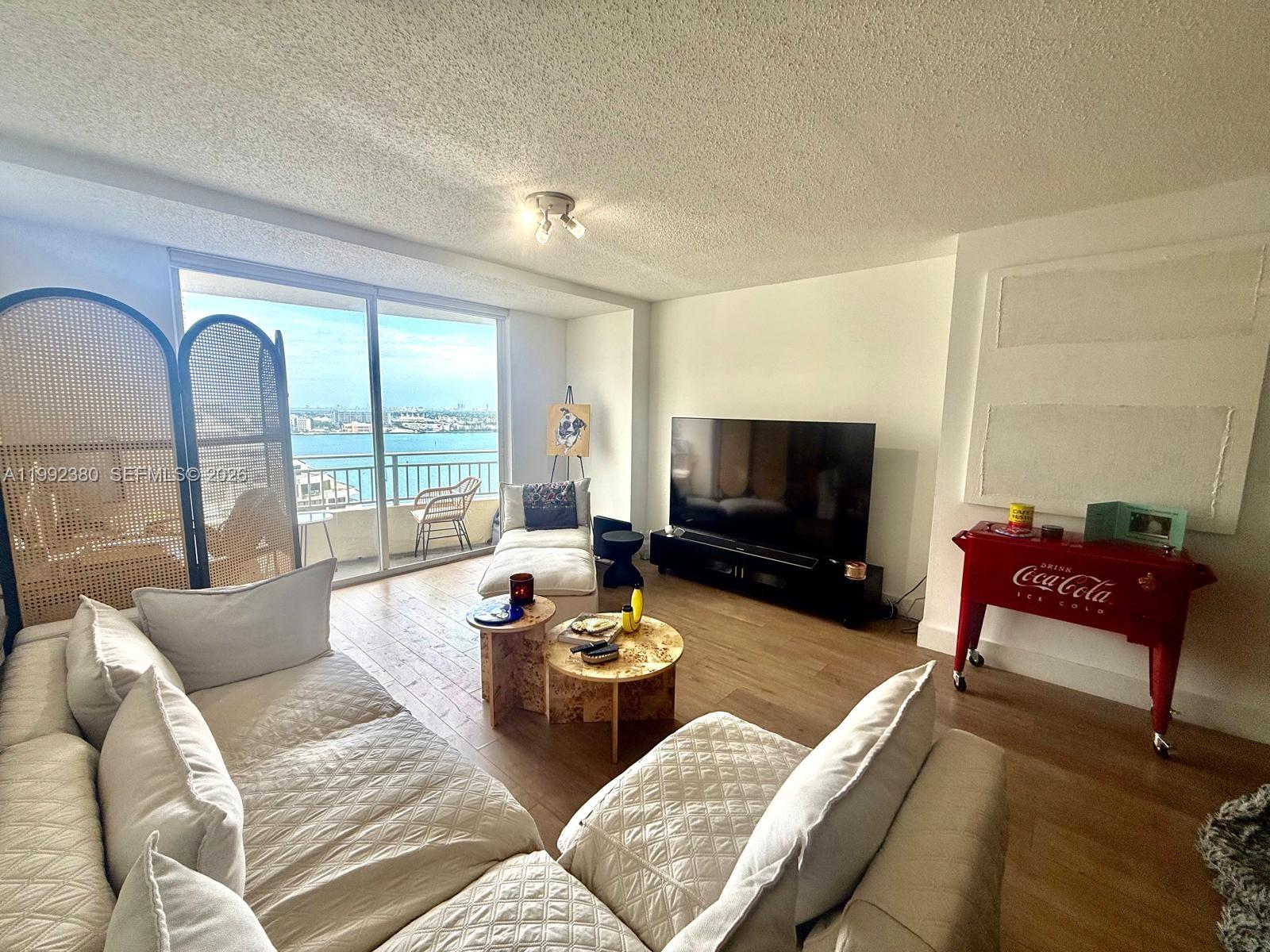 A living room features a white sectional sofa, two round tables, and a balcony view — 770 Claughton Island Dr # 2009, Miami FL 33131, MIAMI, FL