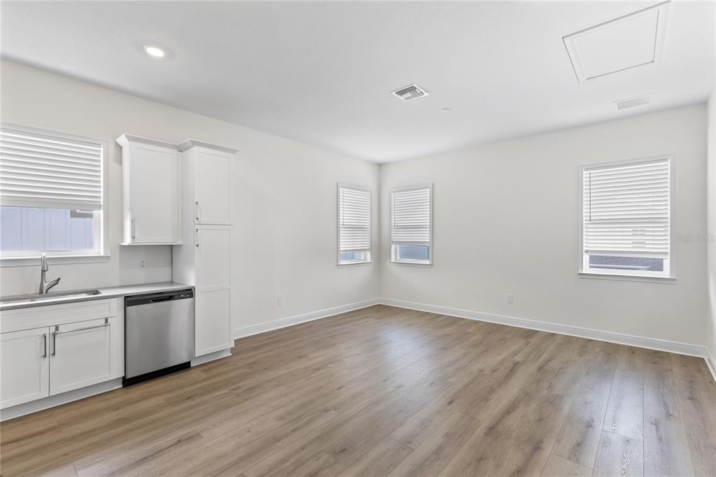 A kitchen area with white cabinets, stainless steel appliances, and light wood-look flooring — 10206 MEDAWAR STREET UNIT B, ORLANDO, FL