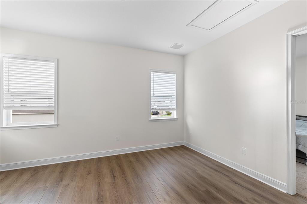 An empty room with light walls, wood-look flooring, and two windows with white blinds — 10206 MEDAWAR STREET UNIT B, ORLANDO, FL