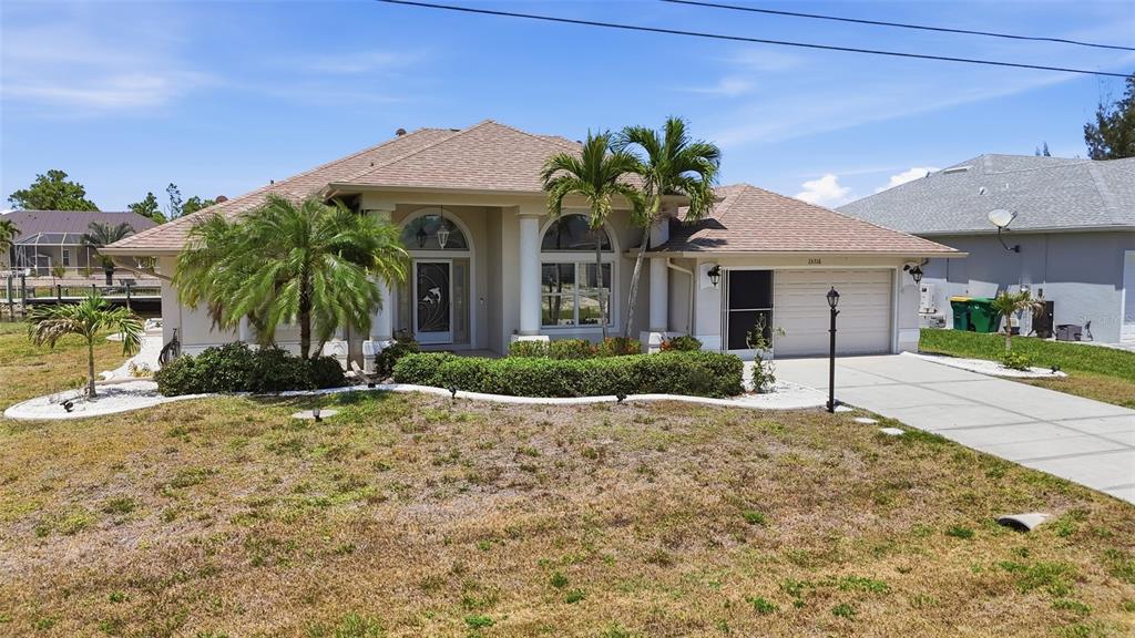A single-story house with a beige exterior, a tan shingled roof, and a front lawn — 15316 RED HEAD AVENUE, PORT CHARLOTTE, FL
