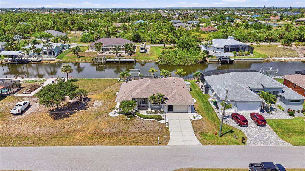 An aerial view shows a suburban house with a canal, dock, and surrounding residential properties — 15316 RED HEAD AVENUE, PORT CHARLOTTE, FL