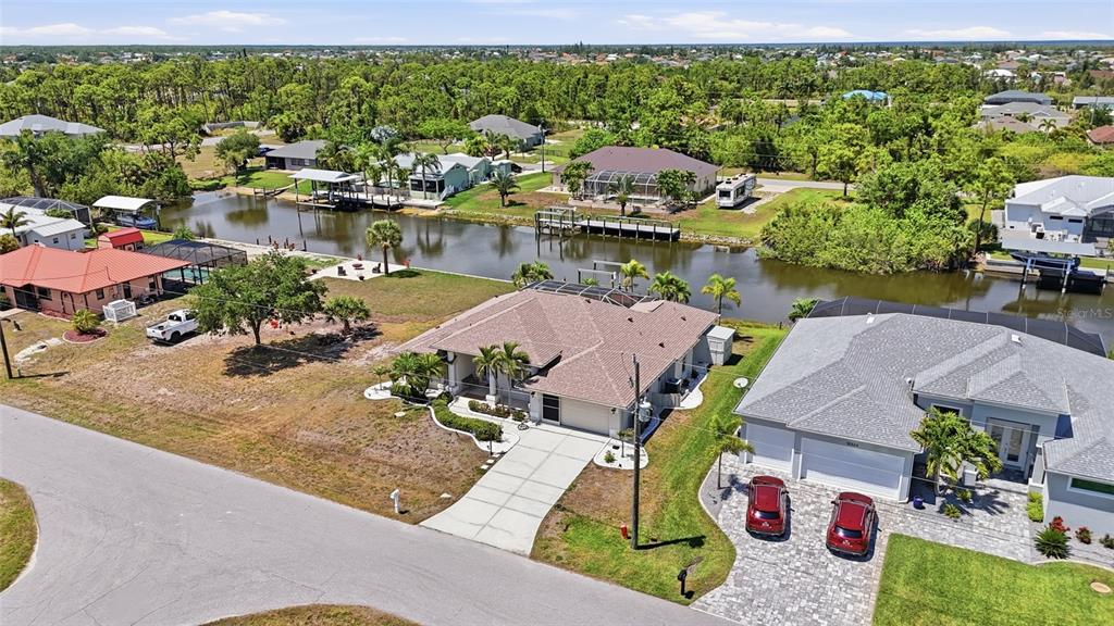 An aerial view shows suburban houses along a canal with docks and surrounding greenery — 15316 RED HEAD AVENUE, PORT CHARLOTTE, FL