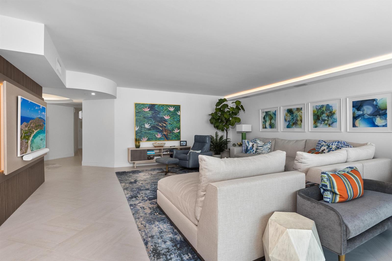 A living room features a large sectional sofa, a blue armchair, and wall-mounted television — 1500 S Ocean Boulevard # 1505, Boca Raton FL 33432, BOCA RATON, FL