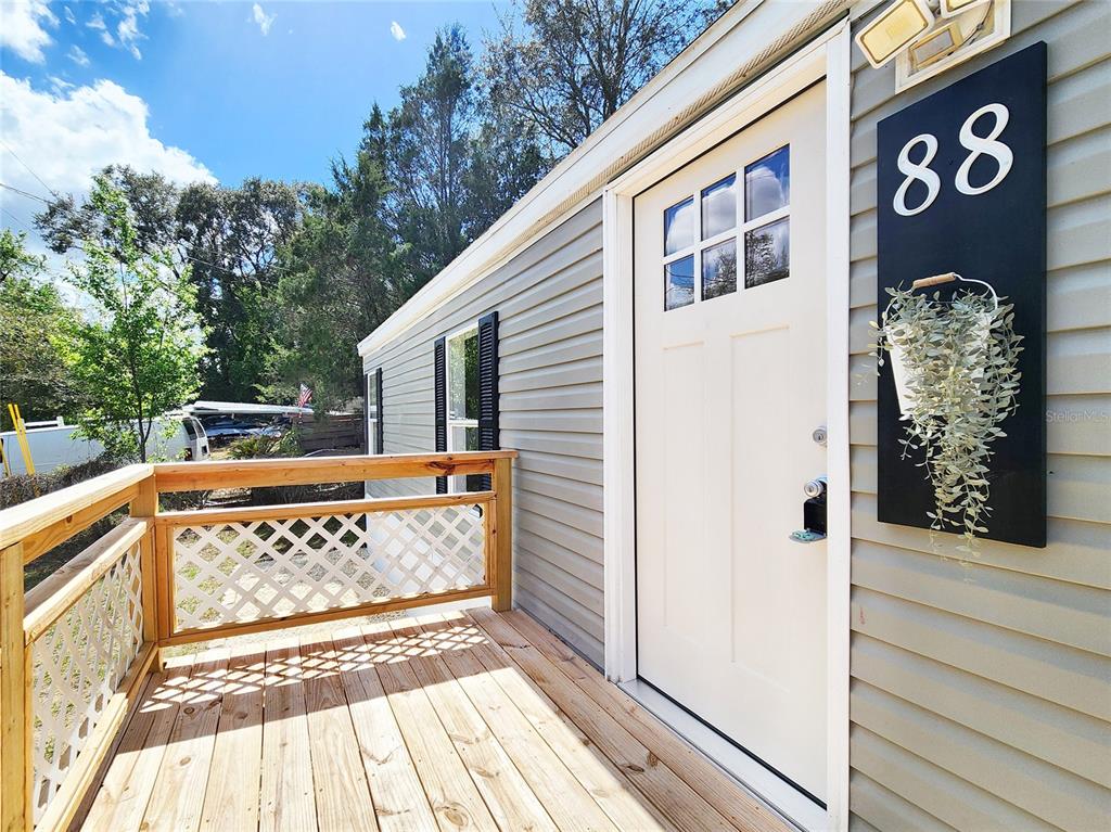 A wooden deck with lattice railings leads to a white door with a house number — 88 N SATURN AVENUE, INVERNESS, FL