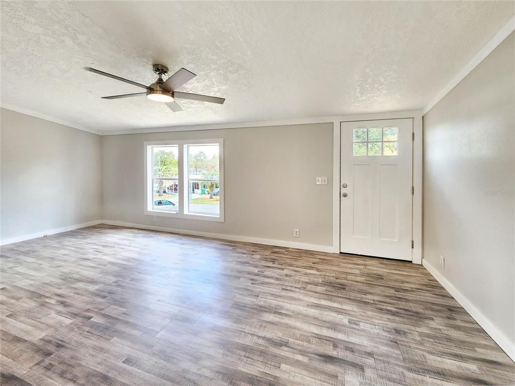 A living room features light gray walls, wood-look flooring, a ceiling fan, and a white door — 88 N SATURN AVENUE, INVERNESS, FL