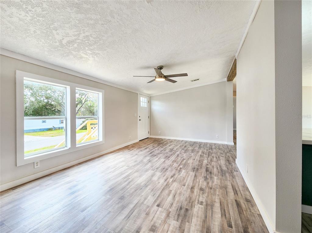 An empty living room features light wood-look flooring, white walls, and a ceiling fan — 88 N SATURN AVENUE, INVERNESS, FL