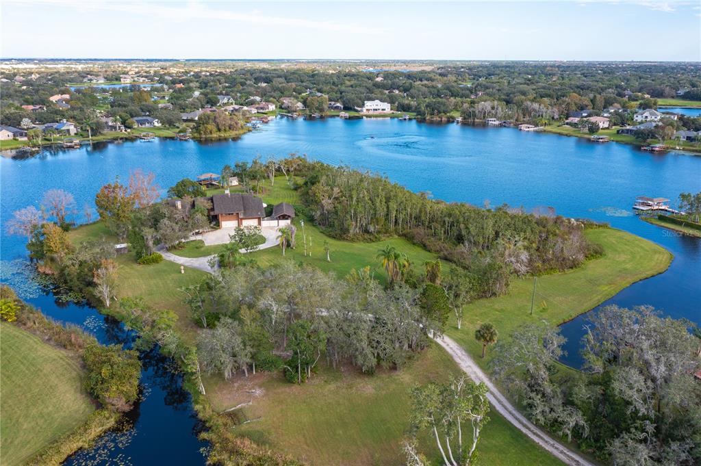 An aerial view shows a house situated on a large, grassy peninsula surrounded by water — 13377 LAKE BUTLER BOULEVARD, WINTER GARDEN, FL