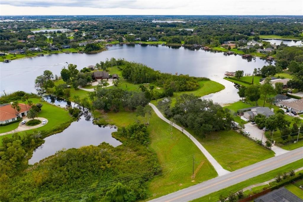 An aerial view shows a house on a peninsula surrounded by a lake and greenery — 13377 LAKE BUTLER BOULEVARD, WINTER GARDEN, FL