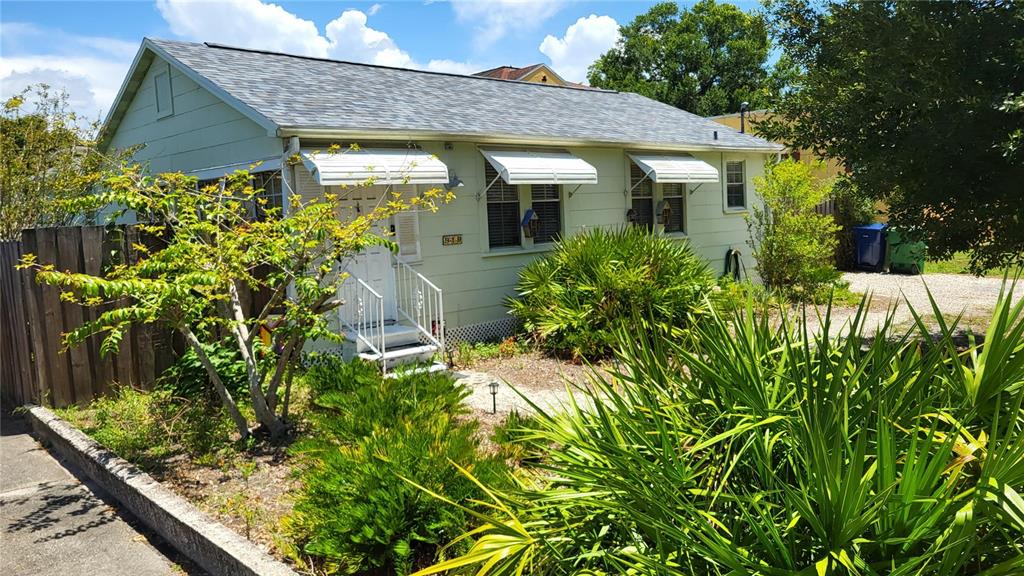 A light green, single-story house with a shingled roof and metal window awnings — 919 W WOODLAWN AVENUE, TAMPA, FL