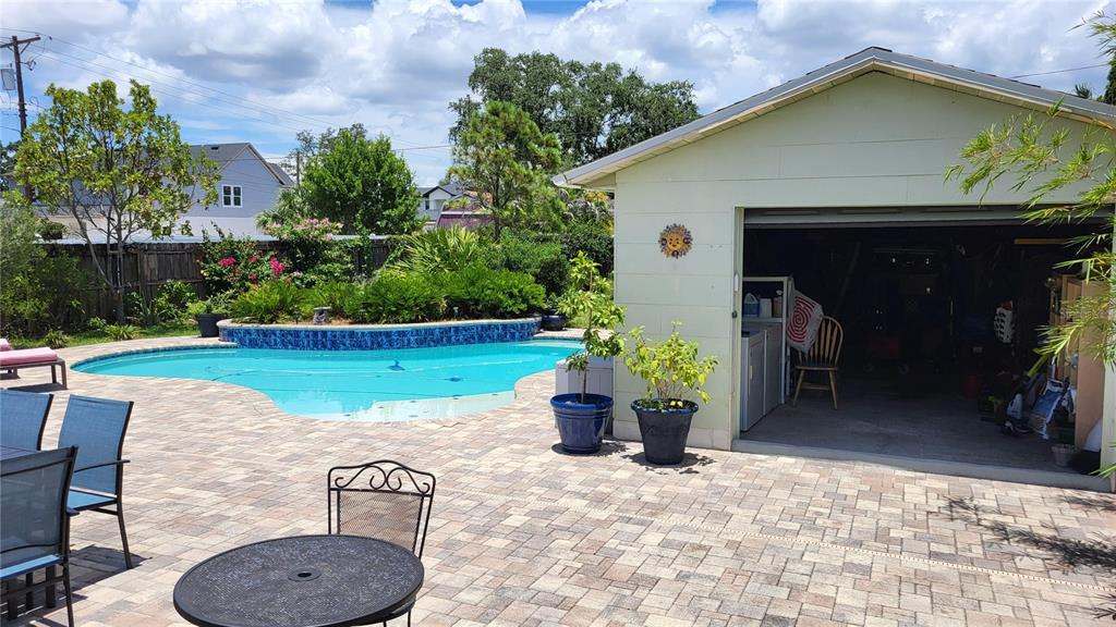 A backyard features a swimming pool, a paved patio, and a detached garage — 919 W WOODLAWN AVENUE, TAMPA, FL