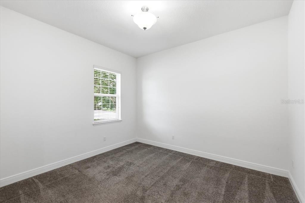 An empty bedroom features white walls, gray carpet, and a single window — 16545 BROADWATER AVENUE, WINTER GARDEN, FL