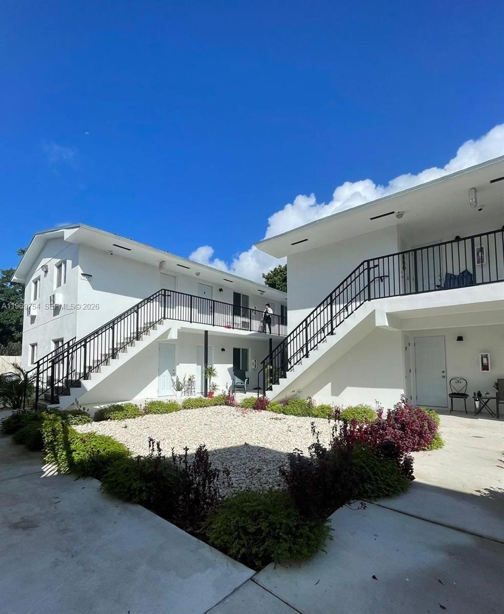 A two-story white apartment building features exterior staircases and a central gravel courtyard — 741 NW 60th St # 3, Miami FL 33127, MIAMI, FL