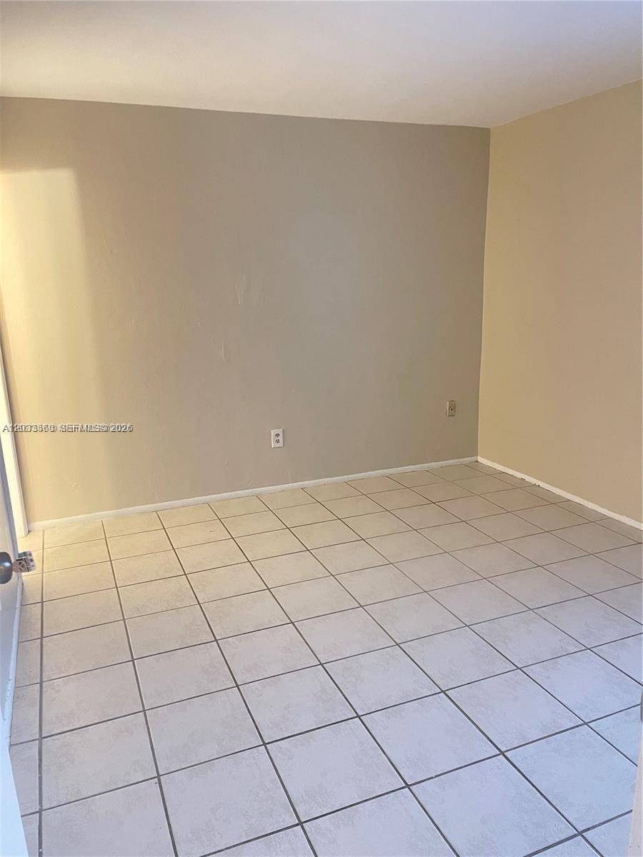 An empty room features light-colored tile flooring and plain beige walls — 10383 N Kendall Dr # N5, Miami FL 33176, MIAMI, FL