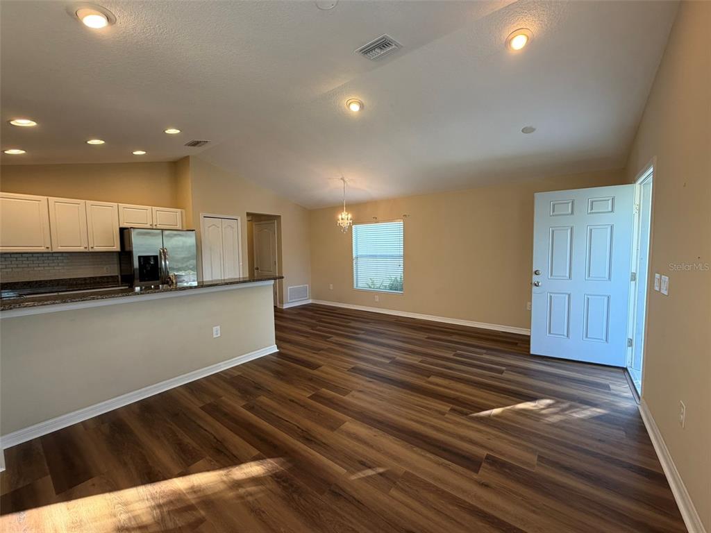 An open-concept kitchen and living area features wood-look flooring, recessed lighting, and a white door — 4735 WOODBROOK DR, SARASOTA, FL