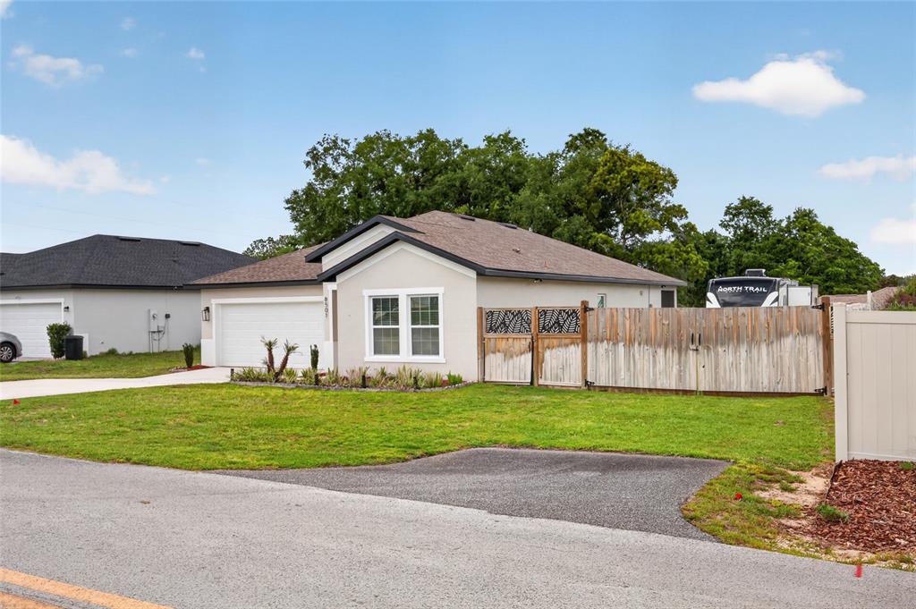 A single-story house with a white exterior, a two-car garage, and a wooden privacy fence — 8501 SE 160TH PLACE, SUMMERFIELD, FL