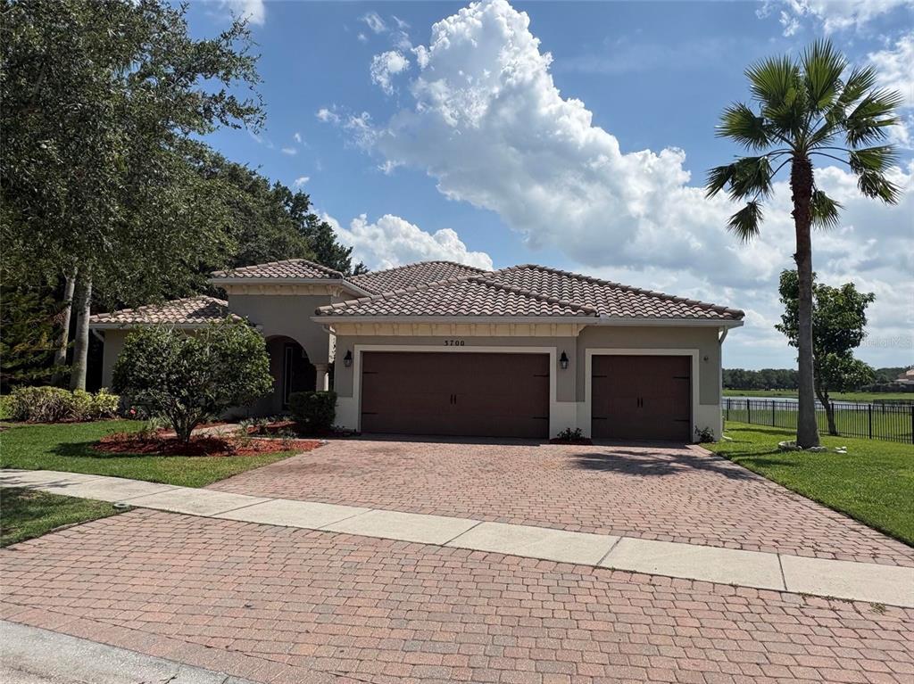 A single-story house with a tiled roof, three-car garage, and a brick paver driveway — 3700 PARADISO CIRCLE, KISSIMMEE, FL