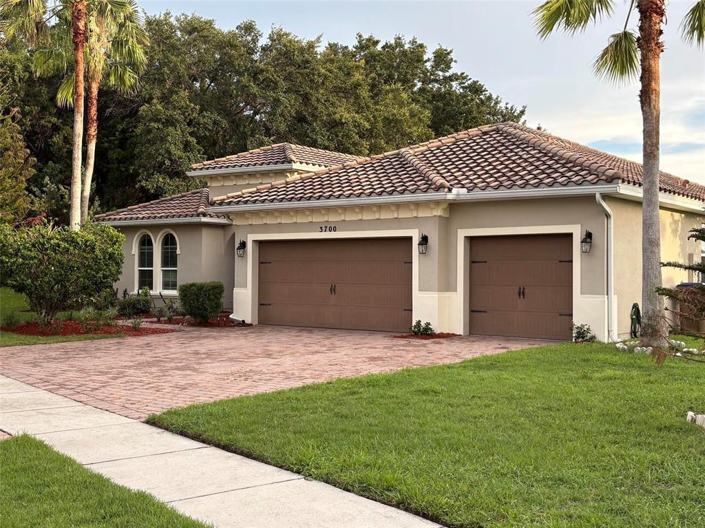 A single-story house with a tile roof, two garage doors, and a brick paver driveway — 3700 PARADISO CIRCLE, KISSIMMEE, FL
