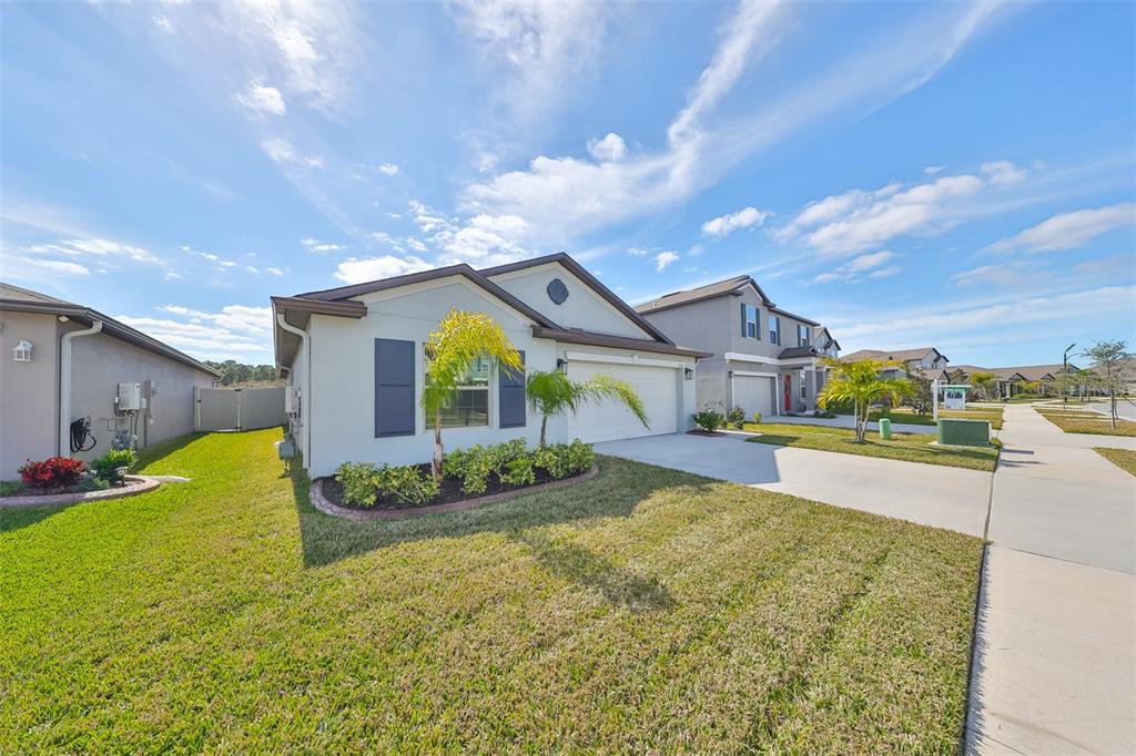 A single-story suburban house with a light-colored exterior, dark shutters, and a concrete driveway — 9316 CHANNING HILL DRIVE, RUSKIN, FL