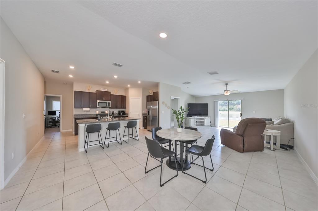 An open-concept kitchen, dining area, and living room featuring tile floors and dark cabinetry — 9316 CHANNING HILL DRIVE, RUSKIN, FL