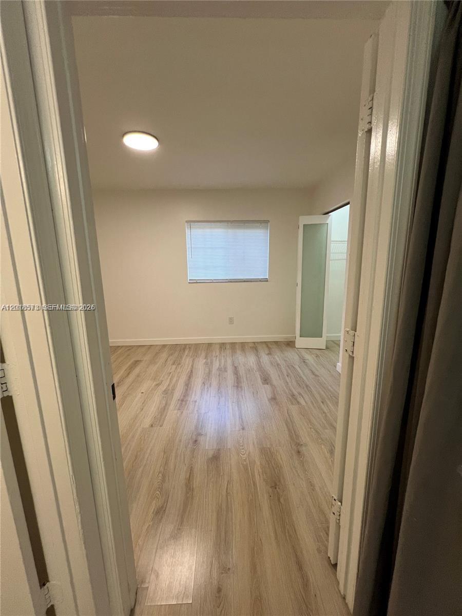 An empty bedroom features light wood-look flooring, white walls, and a window with blinds — 3700 N 56th Ave # 1012, Hollywood FL 33021, HOLLYWOOD, FL
