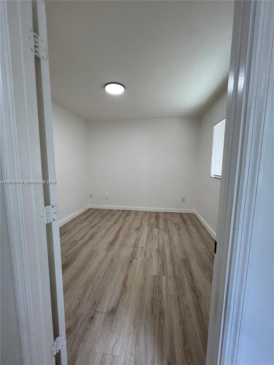 An empty room features white walls, light wood-look flooring, and a single ceiling light — 3700 N 56th Ave # 1012, Hollywood FL 33021, HOLLYWOOD, FL