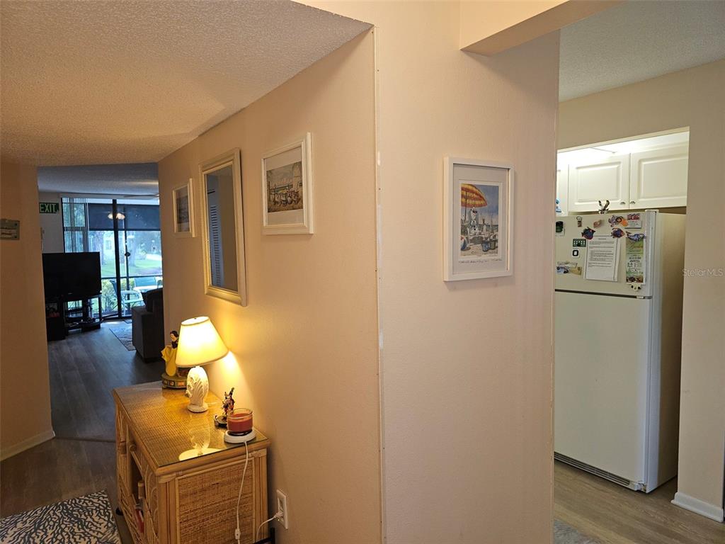 A hallway with a wicker console table leads to a living area and a kitchen — 4655 W 46TH STREET COURT UNIT 103, BRADENTON, FL