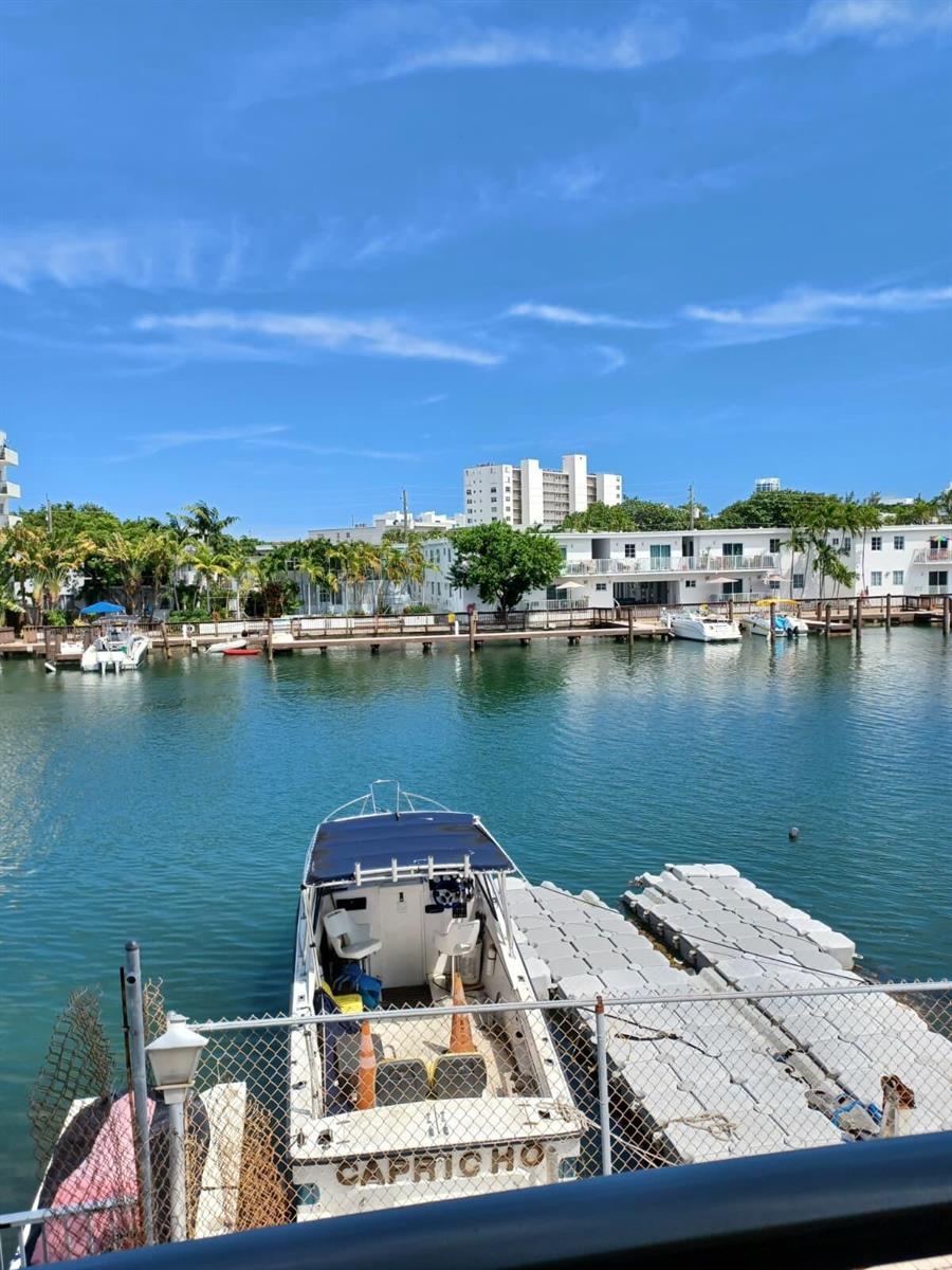 A boat named Capricho is docked at a marina in front of white residential buildings — 8001 N Crespi Boulevard # 2c, Miami Beach FL 33141, MIAMI BEACH, FL