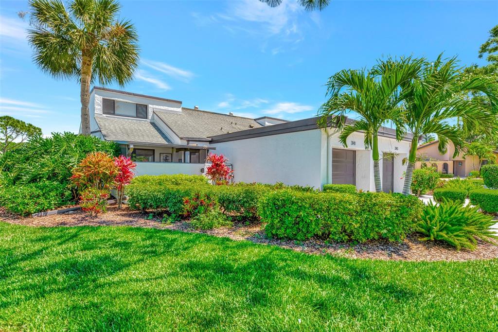 A white, single-story townhouse with a gray roof, palm trees, and manicured landscaping — 3141 HEATHERWOOD LANE, SARASOTA, FL