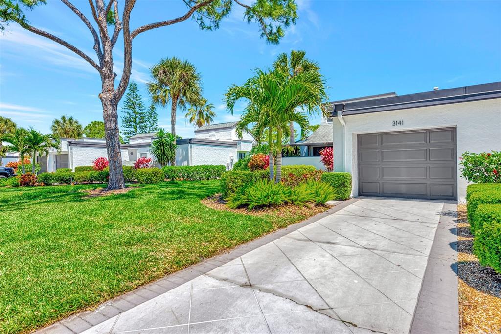 A white house with a gray garage door and a concrete driveway sits on grass — 3141 HEATHERWOOD LANE, SARASOTA, FL