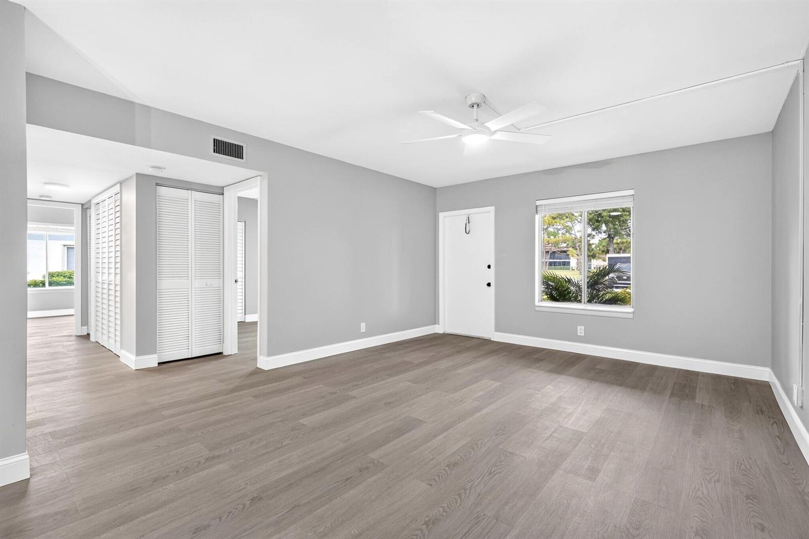 An empty room features gray walls, wood-look flooring, a ceiling fan, and a white door — 6495 Chasewood Drive # B, Jupiter FL 33458, JUPITER, FL