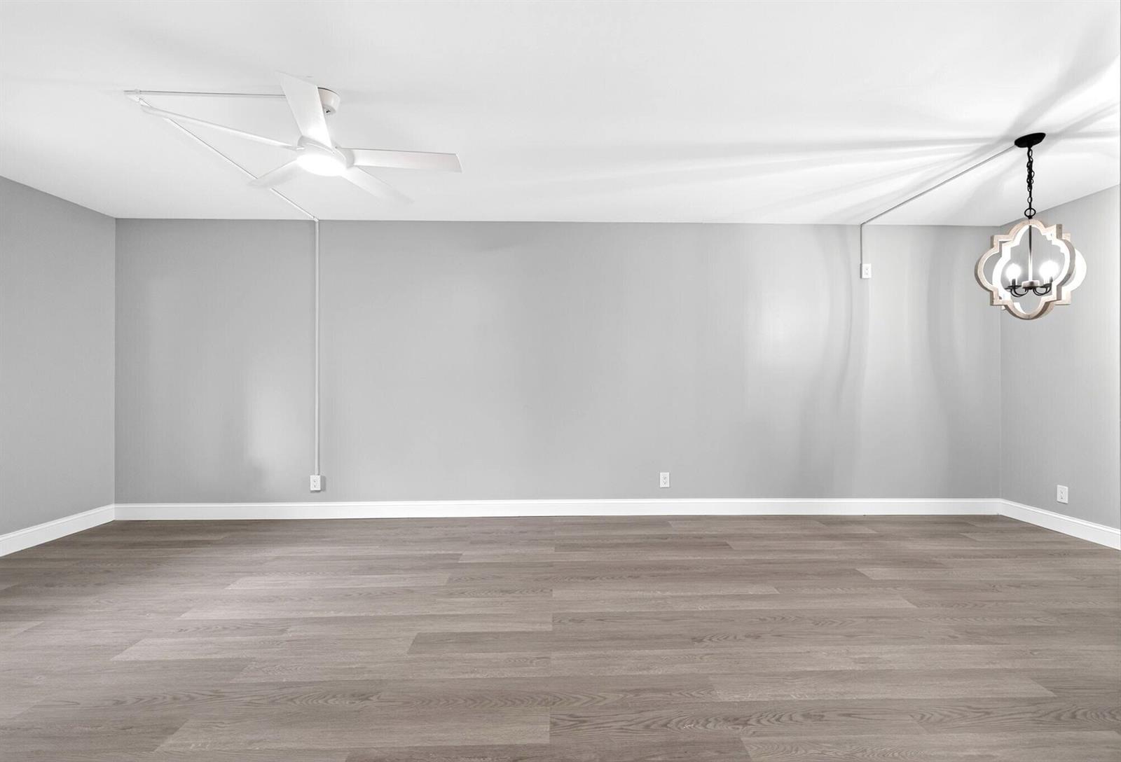 An empty room features gray walls, wood-look flooring, a ceiling fan, and a hanging light — 6495 Chasewood Drive # B, Jupiter FL 33458, JUPITER, FL