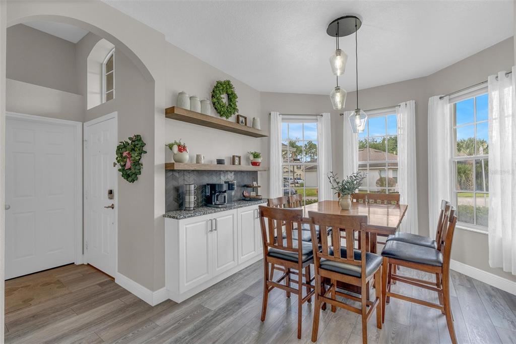 A dining area features a coffee bar with floating shelves, white cabinets, and three windows — 665 MONTARA DRIVE, DAVENPORT, FL