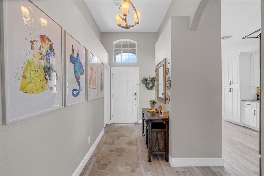 A bright entryway features a patterned runner, framed wall art, a console table, and a chandelier — 665 MONTARA DRIVE, DAVENPORT, FL