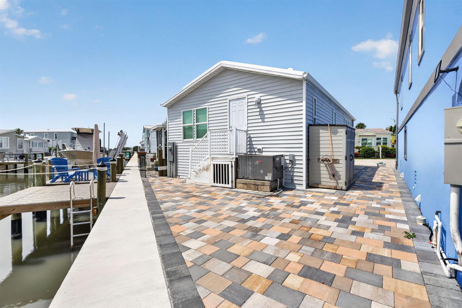 A light gray house with a paved patio sits beside a boat dock and water — 351 Nettles Boulevard, Jensen Beach FL 34957, JENSEN BEACH, FL