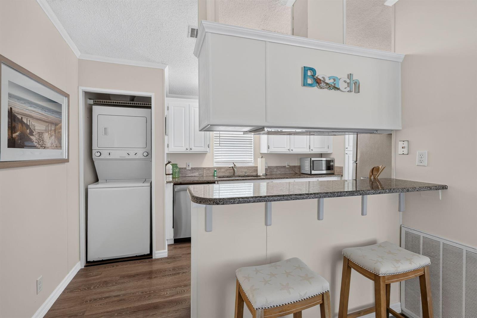 A kitchen features a breakfast bar, white cabinets, granite countertops, and an adjacent laundry closet — 351 Nettles Boulevard, Jensen Beach FL 34957, JENSEN BEACH, FL