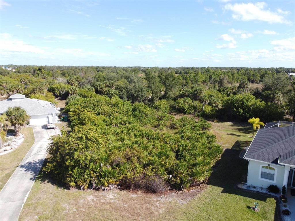 An aerial view shows a vacant, wooded lot situated between two residential houses — 330 BAYTREE DRIVE, ROTONDA WEST, FL