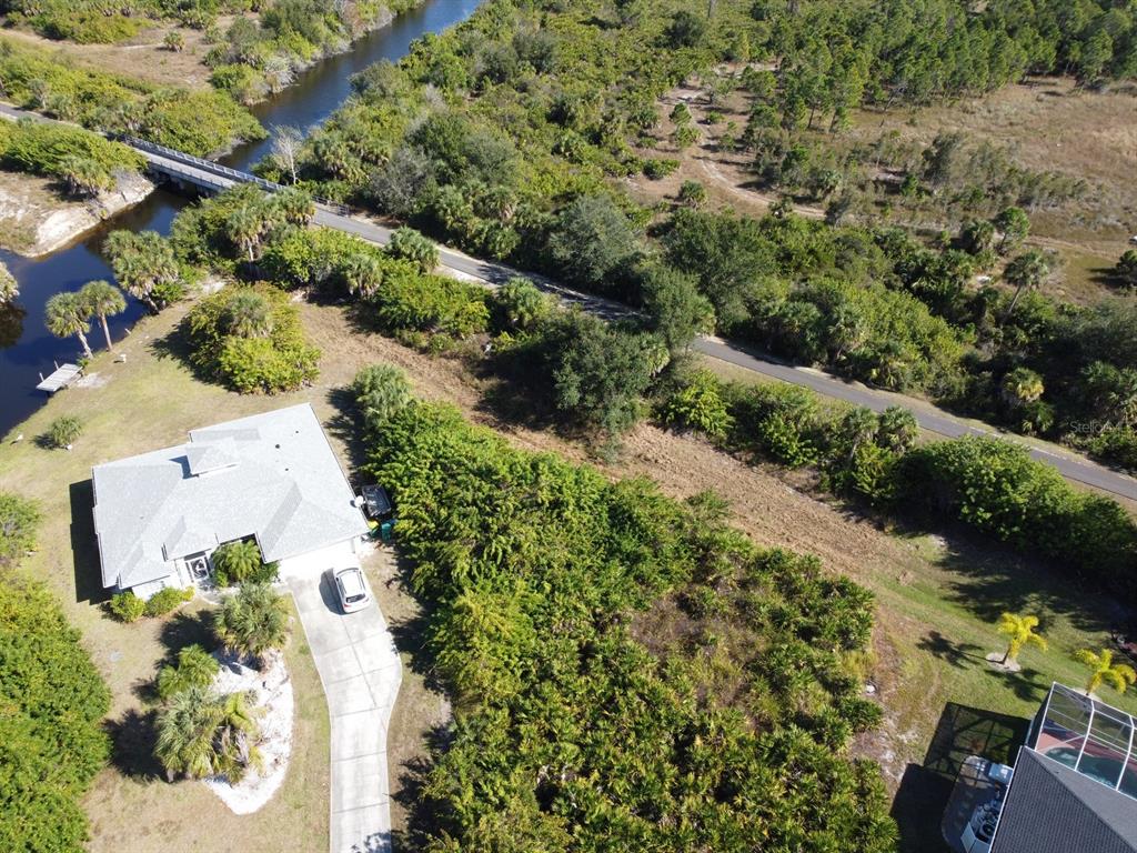 An aerial view shows a house with a driveway, surrounding vegetation, and a nearby bridge — 330 BAYTREE DRIVE, ROTONDA WEST, FL