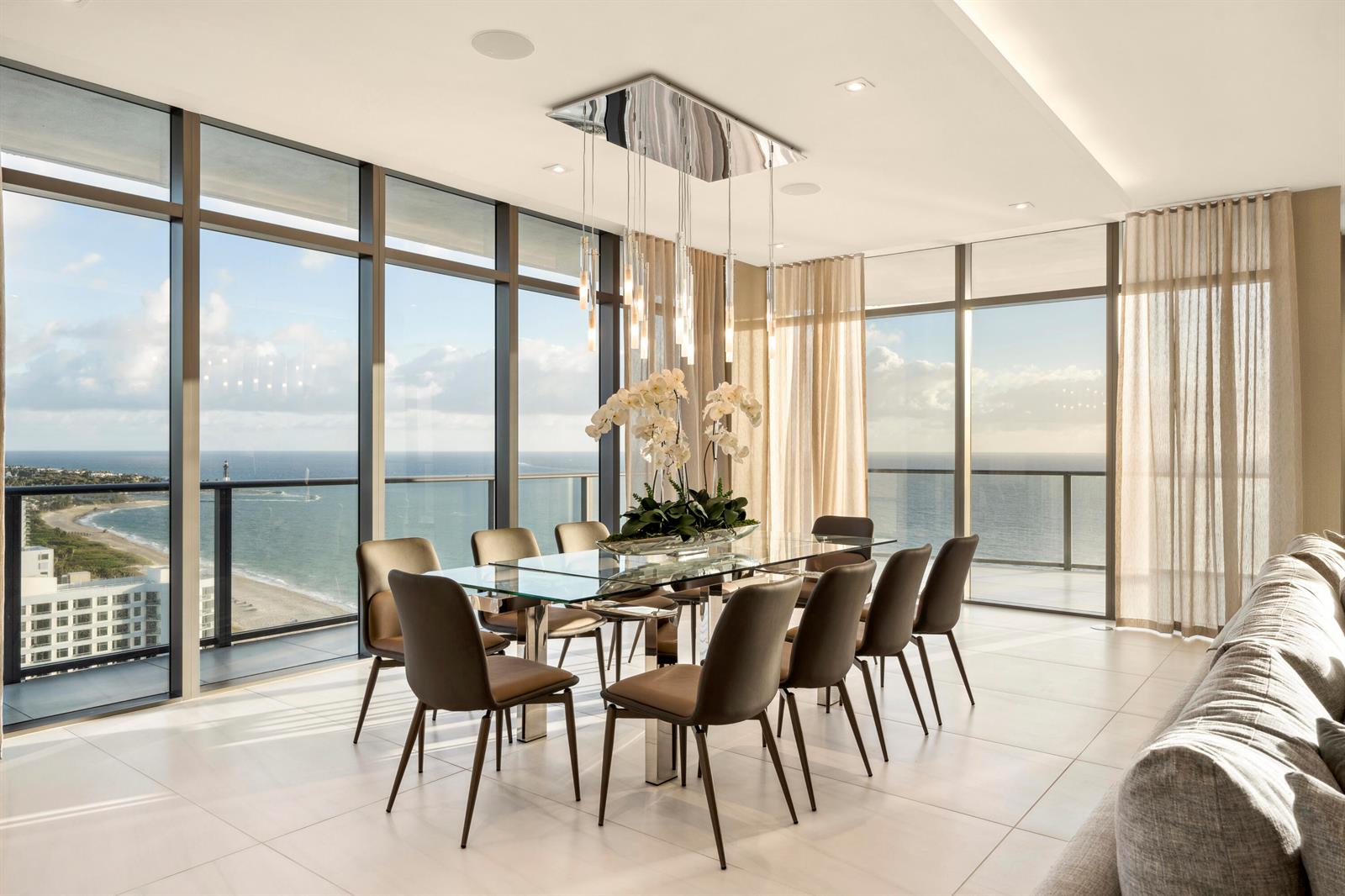 A dining room with a glass table, modern chairs, and floor-to-ceiling windows overlooking the ocean — 1116 N Ocean Boulevard, Pompano Beach FL 33062, POMPANO BEACH, FL