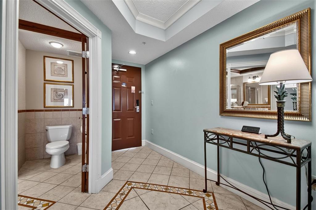 An entryway features tiled floors, a console table with a lamp, and a bathroom door — 200 OCEAN CREST DRIVE UNIT 924, PALM COAST, FL