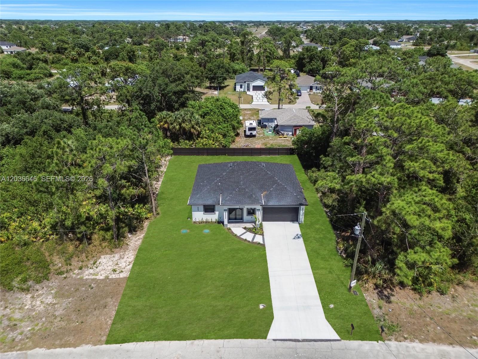 An aerial view shows a single-story house with a dark roof and a concrete driveway — 5035 Spinnaker RD, La Belle FL 33935, LA BELLE, FL