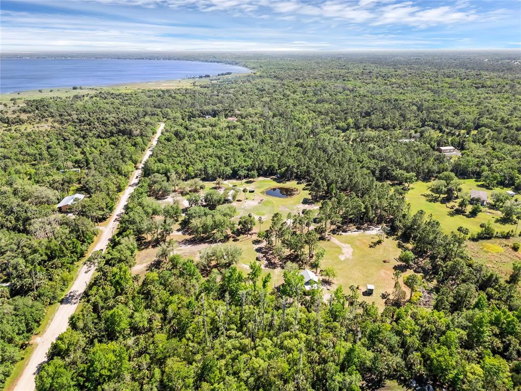 An aerial view shows a rural property with a house, a pond, and dense forest — 2321 WACCASSA STREET, GENEVA, FL