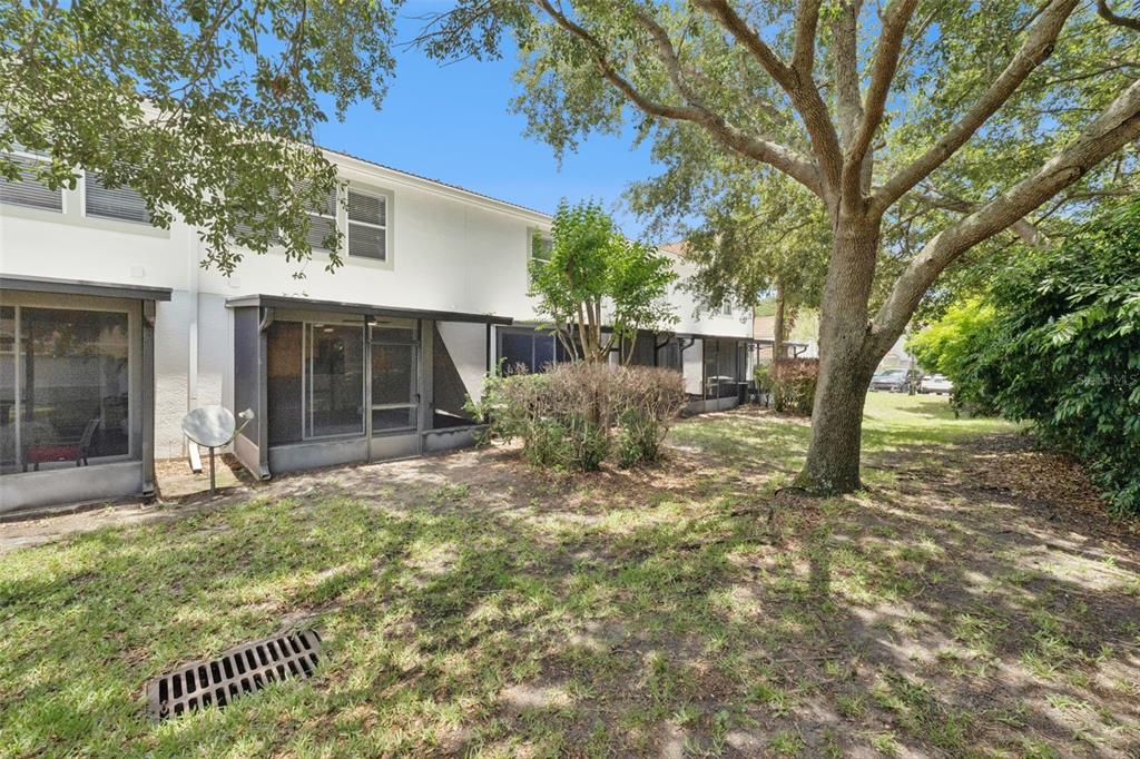The exterior view shows the back of a multi-unit townhouse with screened-in patios and trees — 7138 SHOWCASE LN, ORLANDO, FL
