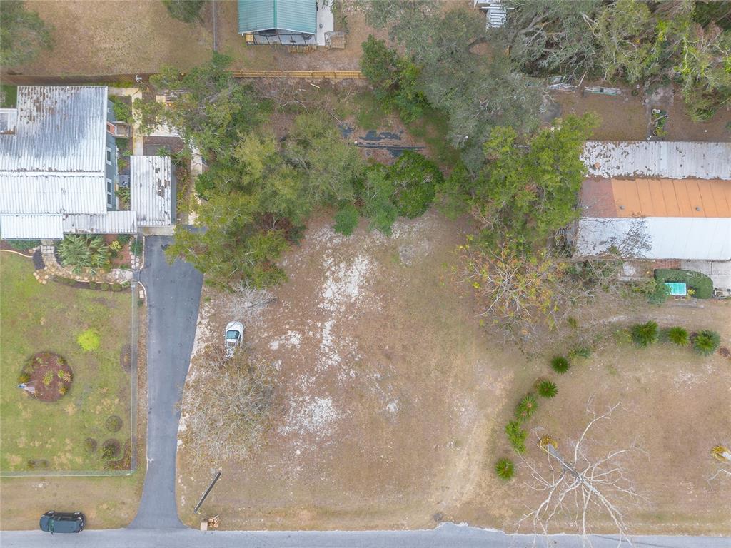 A vacant, grassy residential lot with mature trees and a small structure in the background — 0 SPRING LAKE ROAD, FRUITLAND PARK, FL