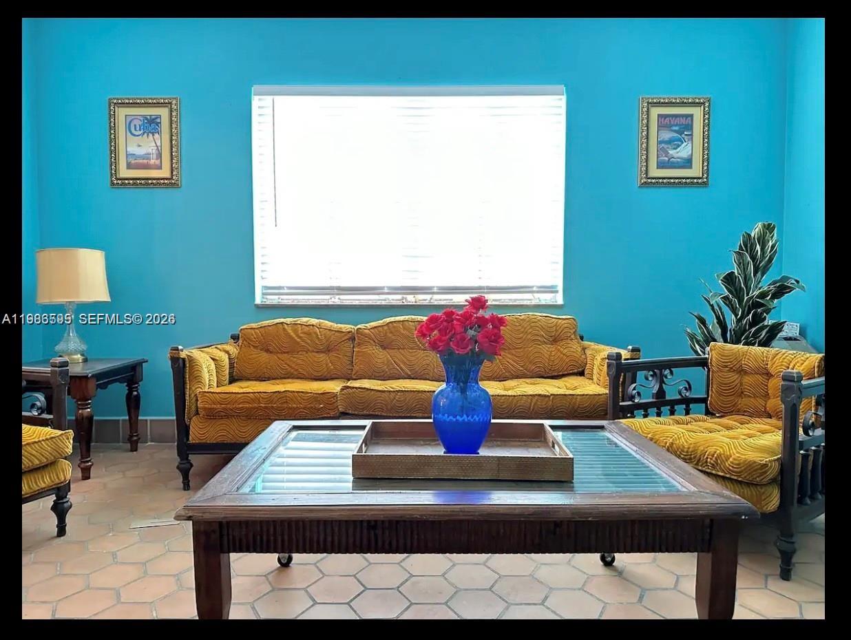 A living room features bright blue walls, yellow textured furniture, and a glass-topped coffee table — 843 NW 3rd St # 1, Miami FL 33128, MIAMI, FL